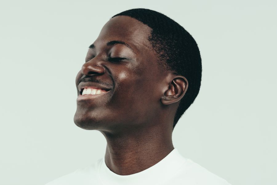 man with glowing skin smiles, looking up eyes closed